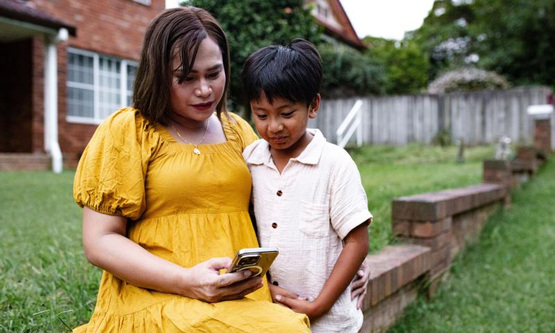 Mother and her child outdoors looking at a phone screen together